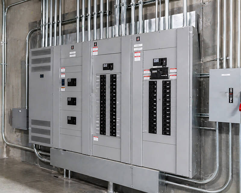 Large commercial electrical panel and switchgear system installed in a warehouse facility with conduit and breakers in Southern California
