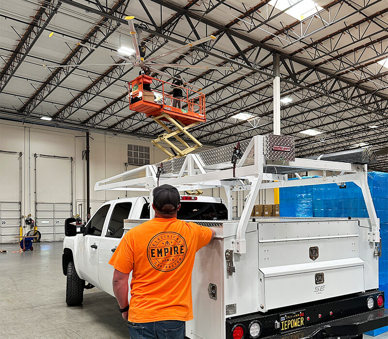 Empire Power technician overseeing HVLS fan installation in a commercial warehouse facility in Southern California