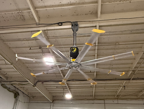 HVLS ceiling fan operating in industrial warehouse to improve air circulation and reduce heat buildup in Southern California facility